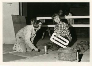 Two students work on the lettering of the 1964 float “Cutting The Apron Strings.”