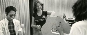 An archival photo of students decorate the lettering on a float in the 1970’s.
