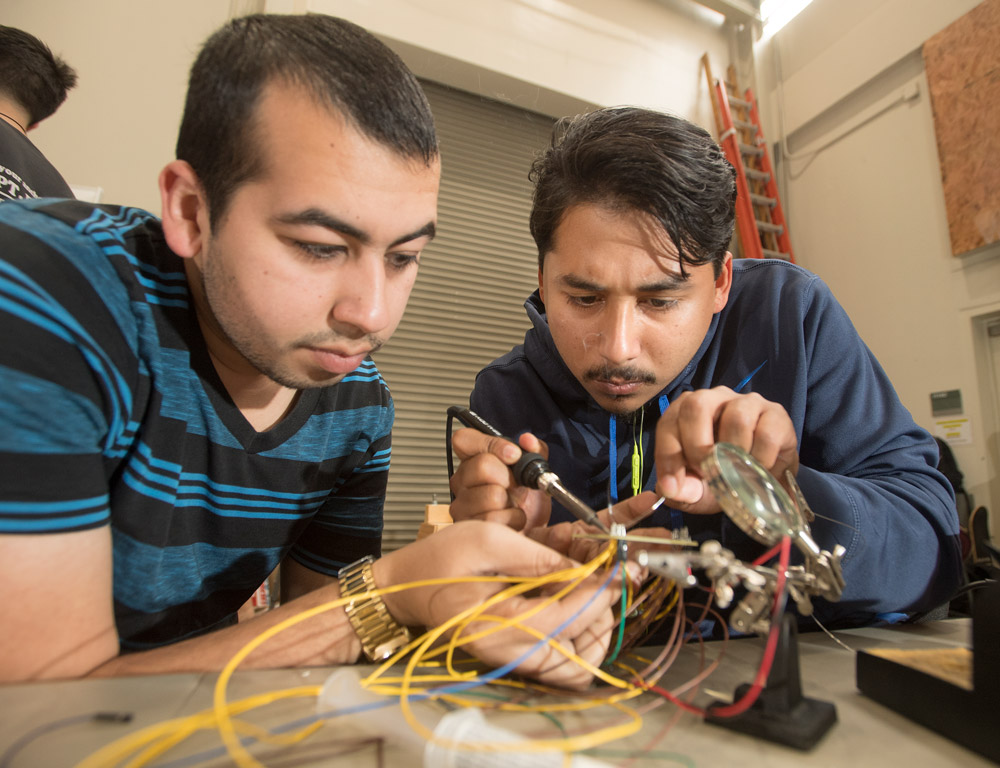Andres Colon and Brian Tapia, both electrical engineering students, solder connections for the sensors.