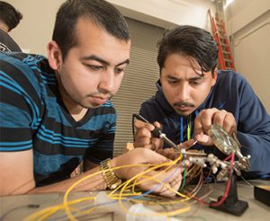 Andres Colon and Brian Tapia, both electrical engineering students, solder connections for the sensors.