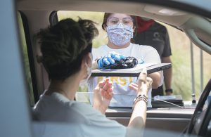 A staff member handing out a laptop to someone in a car
